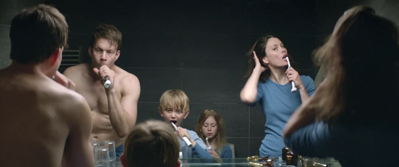 Force Majeure (2014) movie still: medium — A modern tiled bathroom features a large mirror reflecting a family grooming together. An adult man and…