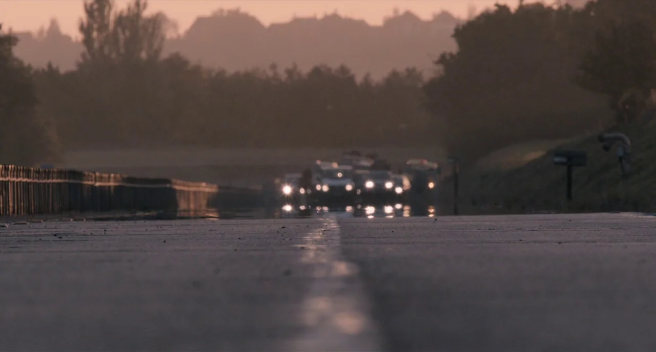 The Selfish Giant (2013) movie still: establishing — A wet asphalt highway stretches toward a horizon lined with silhouettes of distant trees.…