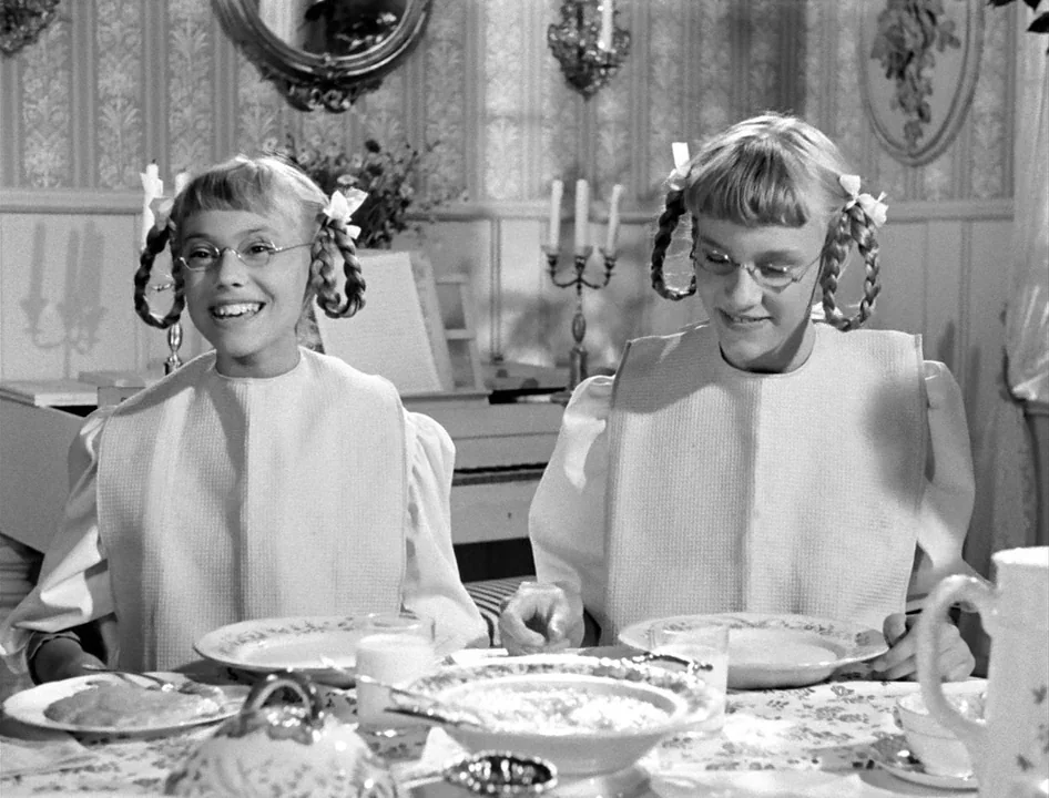 Wild Strawberries (1957) movie still: medium — A traditional dining area with patterned wallpaper, candlesticks, and a floral-patterned tablecloth.…