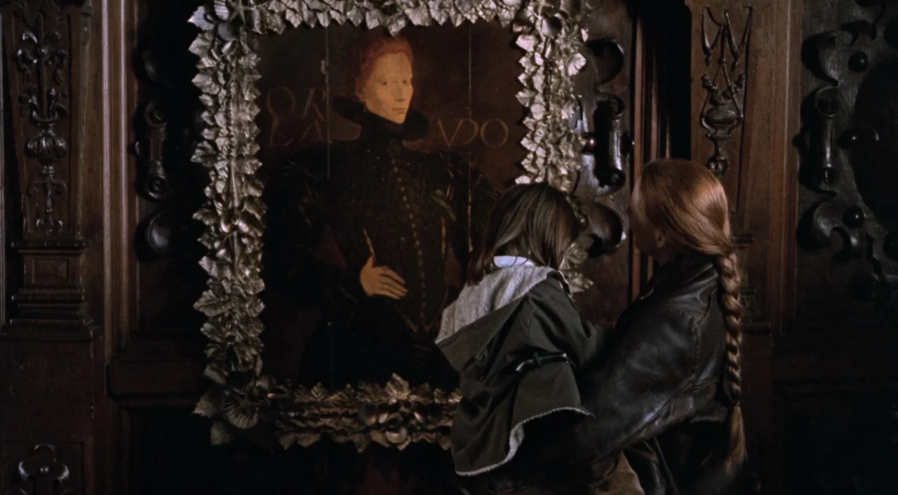Orlando (1992) movie still: medium — An interior space features dark wood paneling and an ornate, leaf-framed portrait on wall. A woman with a braid…