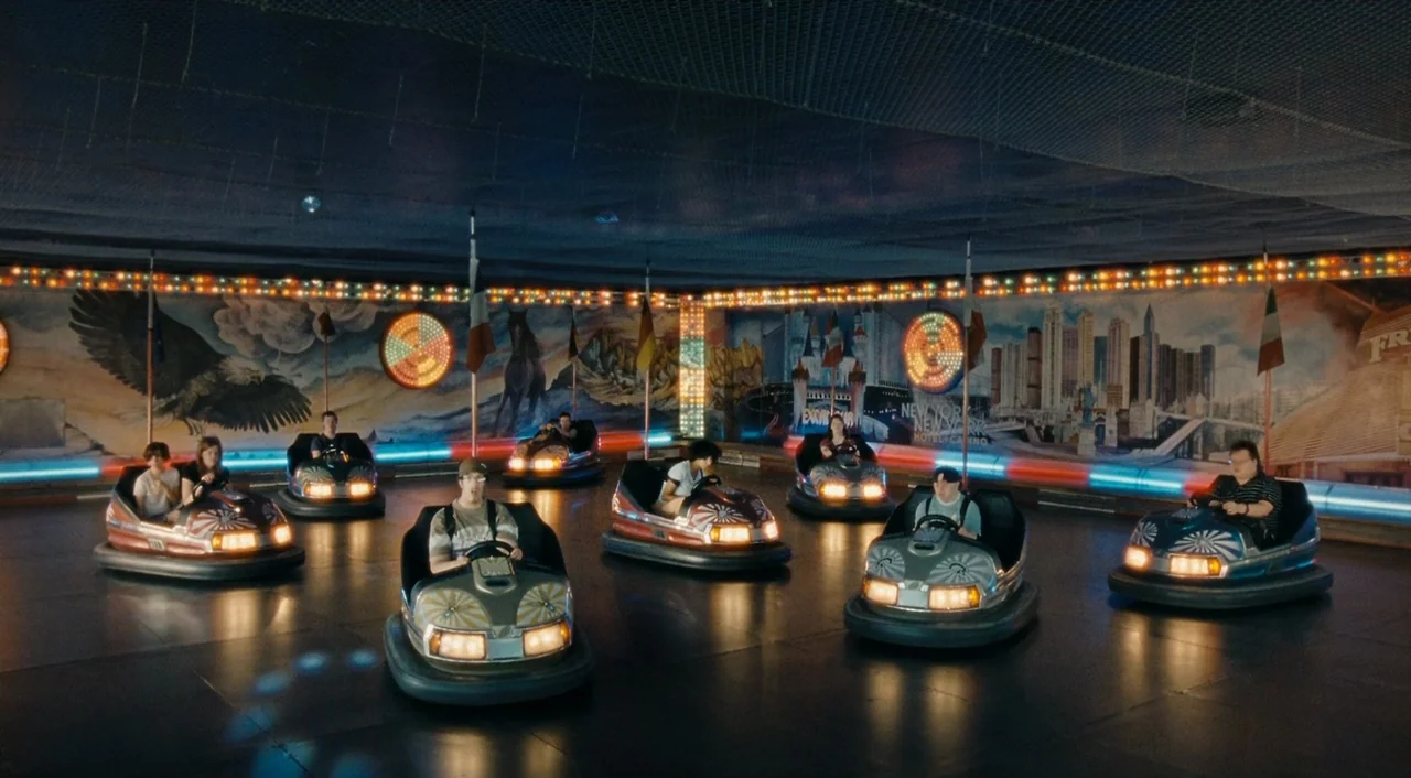 Paradise: Love (2012) movie still: wide — An indoor bumper car arena features a mural of city buildings and an eagle. Several people sit in separate…