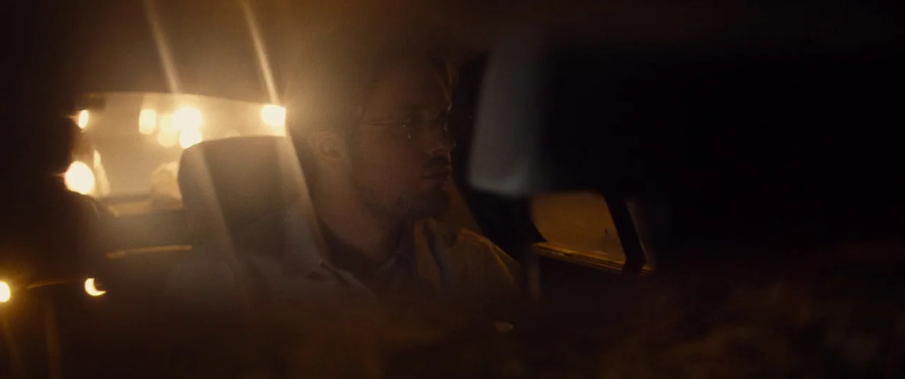 I Origins (2014) movie still: medium — A dark car interior at night illuminated by passing orange city lights. A young man sits in the back seat…