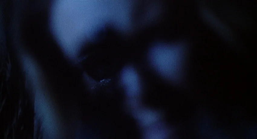 5 Dolls for an August Moon (1970) movie still: closeup — A dark, underexposed shot shows a partial human face emerging from blackness. Only the eye…
