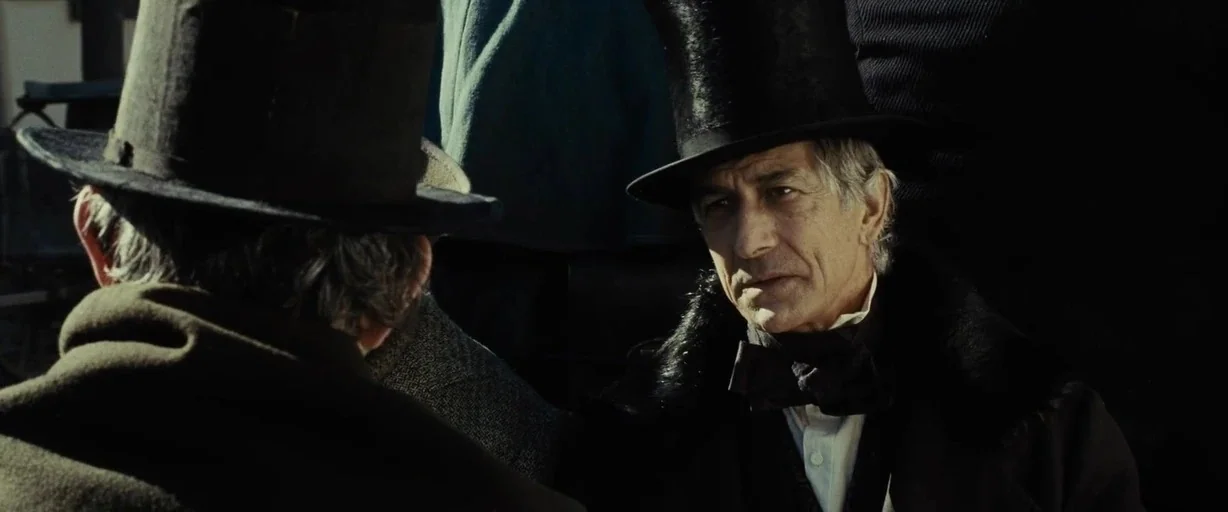 Lincoln (2012) movie still: medium — Two men in dark 19th-century formal wear stand closely together outdoors in sunlight. One man turns toward the…