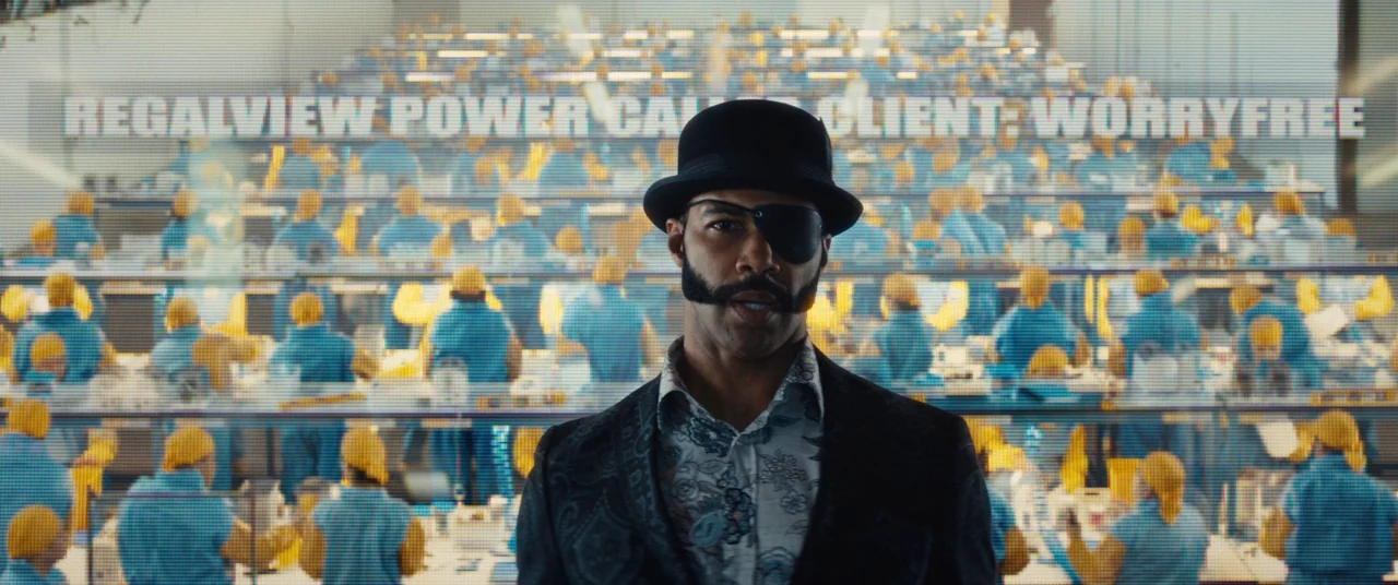 Sorry to Bother You (2018) movie still: medium — A large industrial space is filled with many workers in blue uniforms and yellow hats. A man in a…