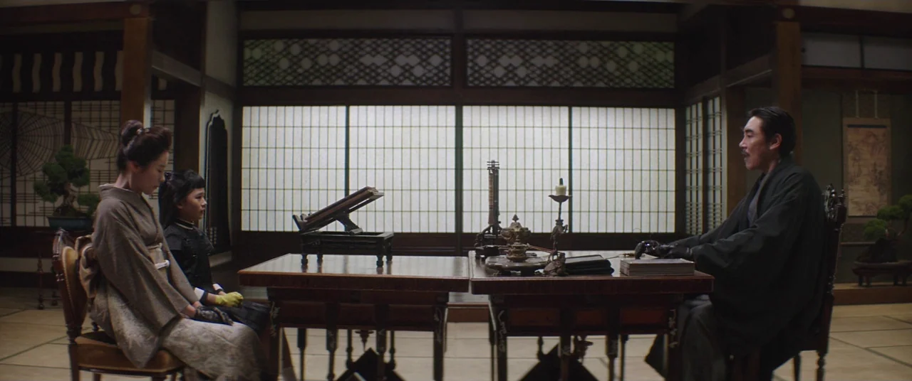 The Handmaiden (2016) movie still: wide — A Japanese room features shoji screens and tatami flooring, with a central wooden table. An adult man sits…