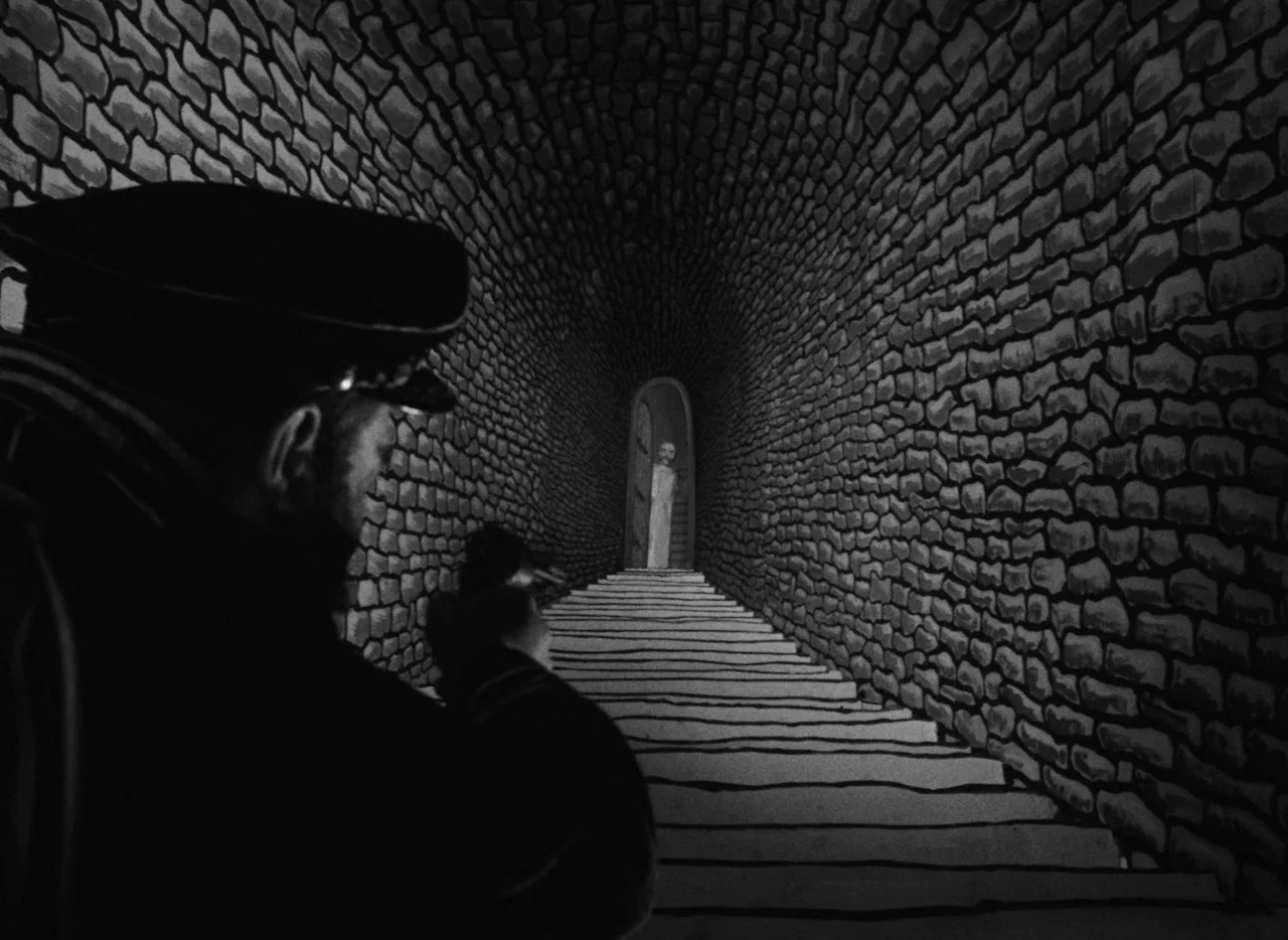 Invention For Destruction (1958) movie still: medium — A stone-walled tunnel with a central staircase leads to a small arched doorway. A person in a…