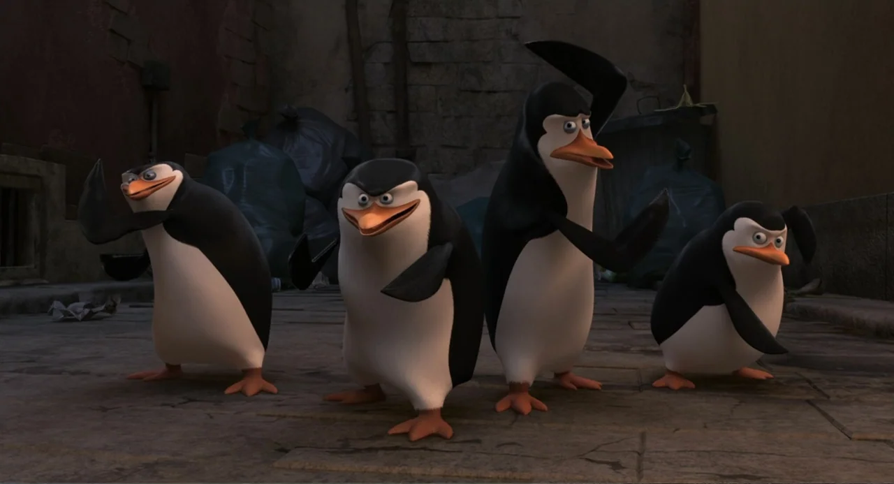 Penguins of Madagascar (2014) movie still: fullbody — A stone alleyway is littered with black trash bags near a brick wall background. Four animated…