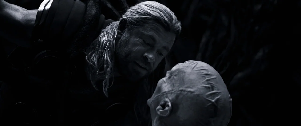 Thor: Love and Thunder (2022) movie still: closeup — A dark, void-like location with no visible background features. A muscular man with long hair…