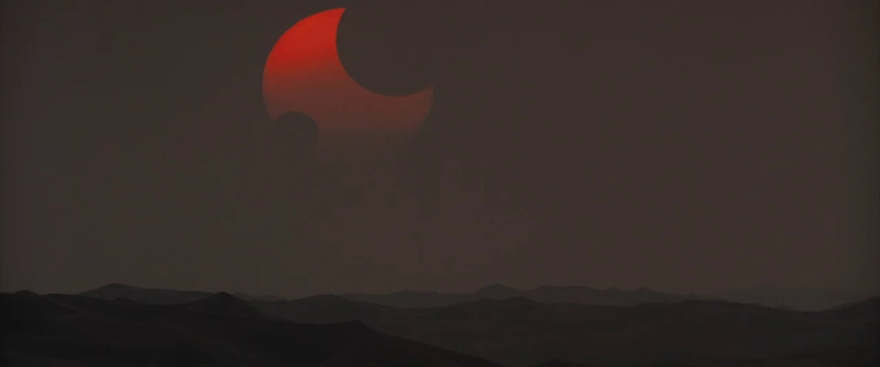 Dune: Part 2 (2024) movie still: establishing — A dark, rolling landscape of sand dunes stretches across the lower portion of the frame. A partially…