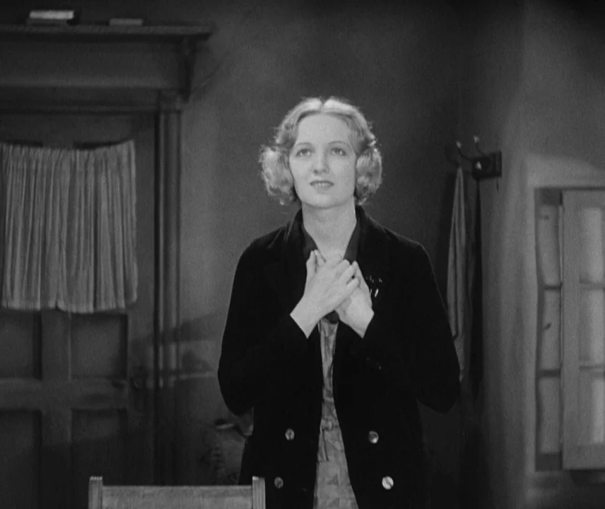 City Lights (1931) movie still: medium — A sparsely furnished room contains a dark wooden door with a small curtained window. A young woman stands…