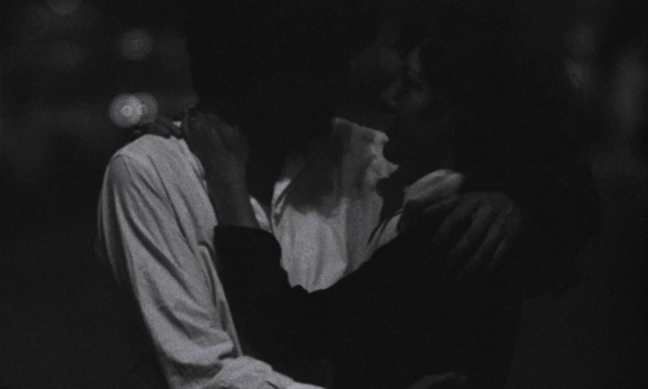 The Secret Son (1979) movie still: medium — A dark night setting with distant blurred city lights visible in the background. Two individuals stand…