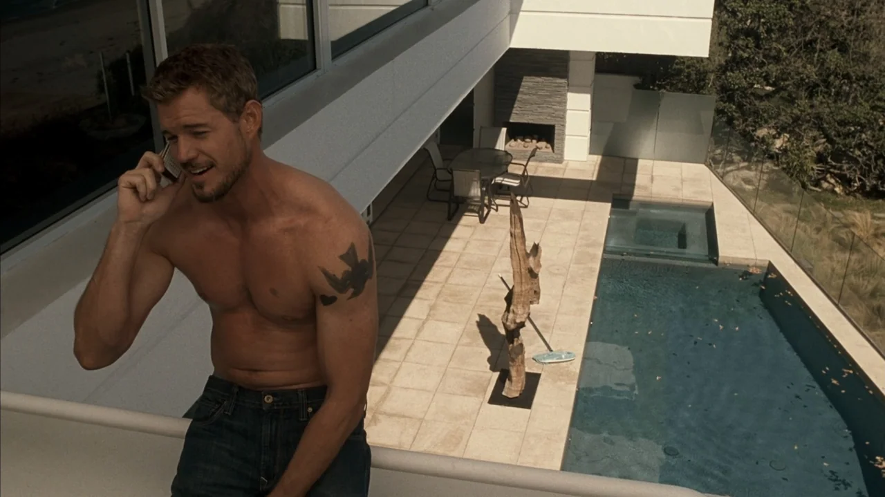 F Valentine's Day (2026) movie still: medium — A modern luxury home balcony with a glass railing overlooks a rectangular swimming pool. A shirtless…
