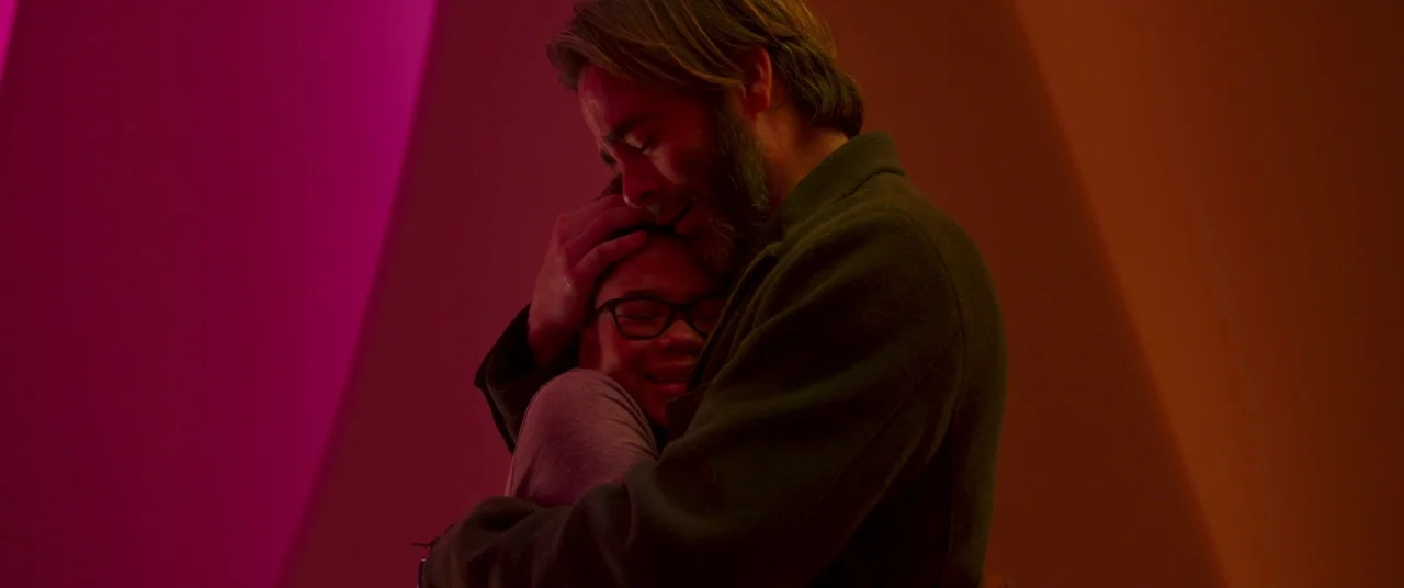 A Wrinkle In Time (2018) movie still: medium — A man and a boy are embraced tightly against a wall in a corridor. The corridor is lit by intense…