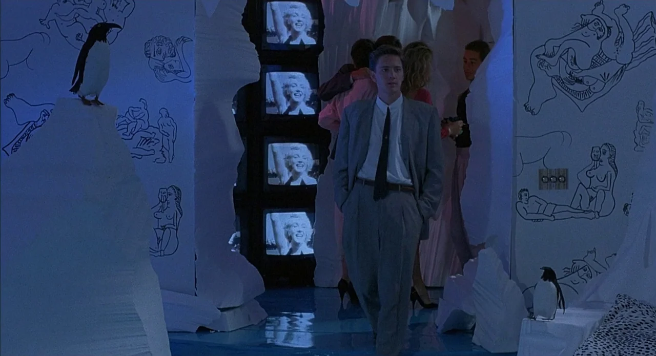 Less Than Zero (1987) movie still: fullbody — A room features white walls decorated with black ink drawings and cut-out foam pillars. A man in a…
