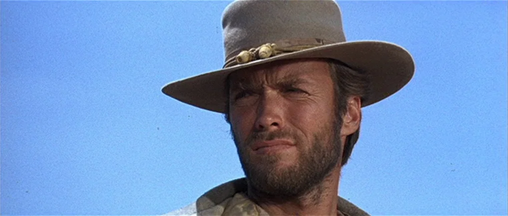 The Good, The Bad And The Ugly (1966) movie still: closeup — An open landscape under a clear, bright blue sky provides a simple backdrop. A man in a…