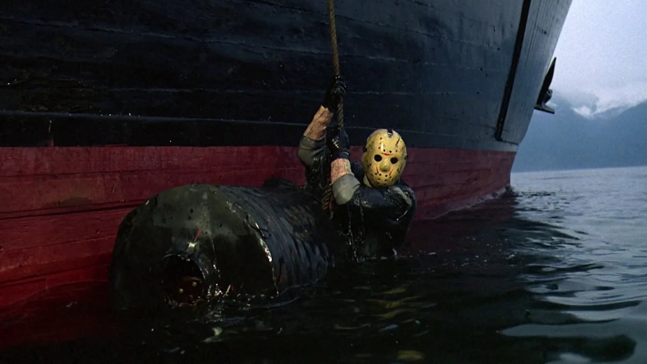 Friday the 13th Part VIII: Jason Takes Manhattan (1989) movie still: medium — A dark ship hull with a red waterline sits partially submerged in calm…