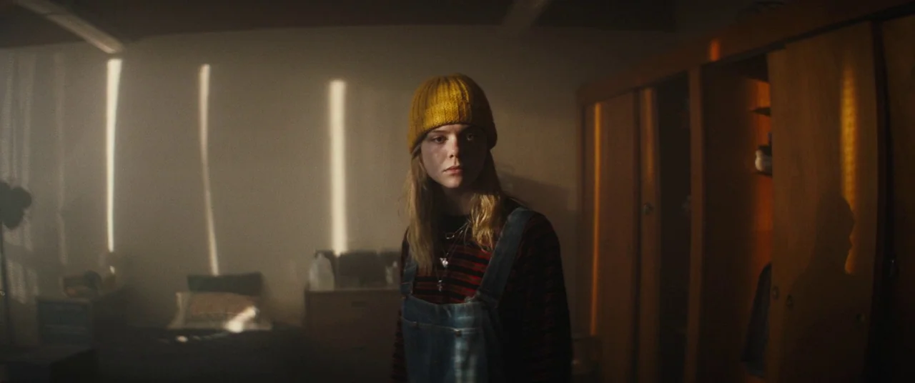 I Think We’re Alone Now (2018) movie still: medium — A dimly lit room features a bed and a wooden wardrobe. The young woman stands in the center…