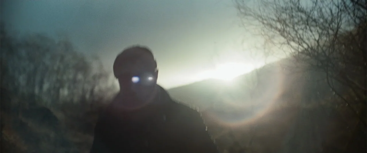 My Son (2021) movie still: medium — A figure walks towards the camera against a sunlit hill during the golden hour. The silhouette of the person…