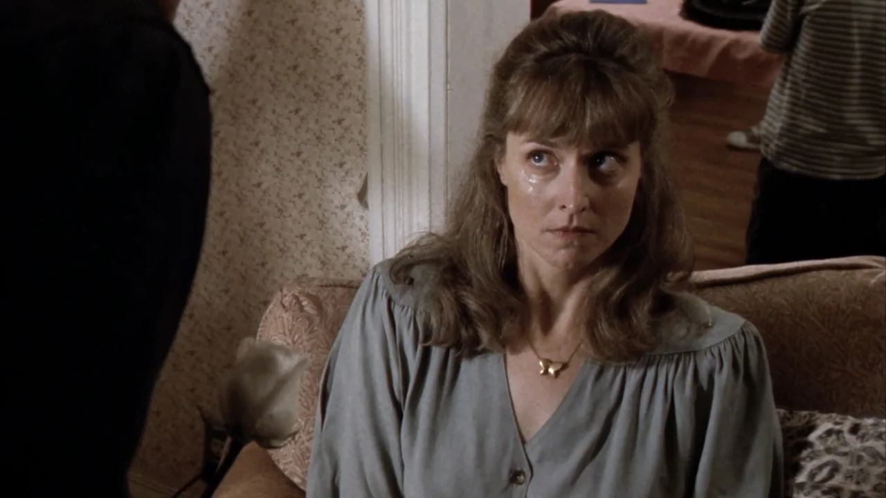 Suspect Zero (2004) movie still: medium — A residential living room features patterned wallpaper and a cushioned sofa in the background. A…