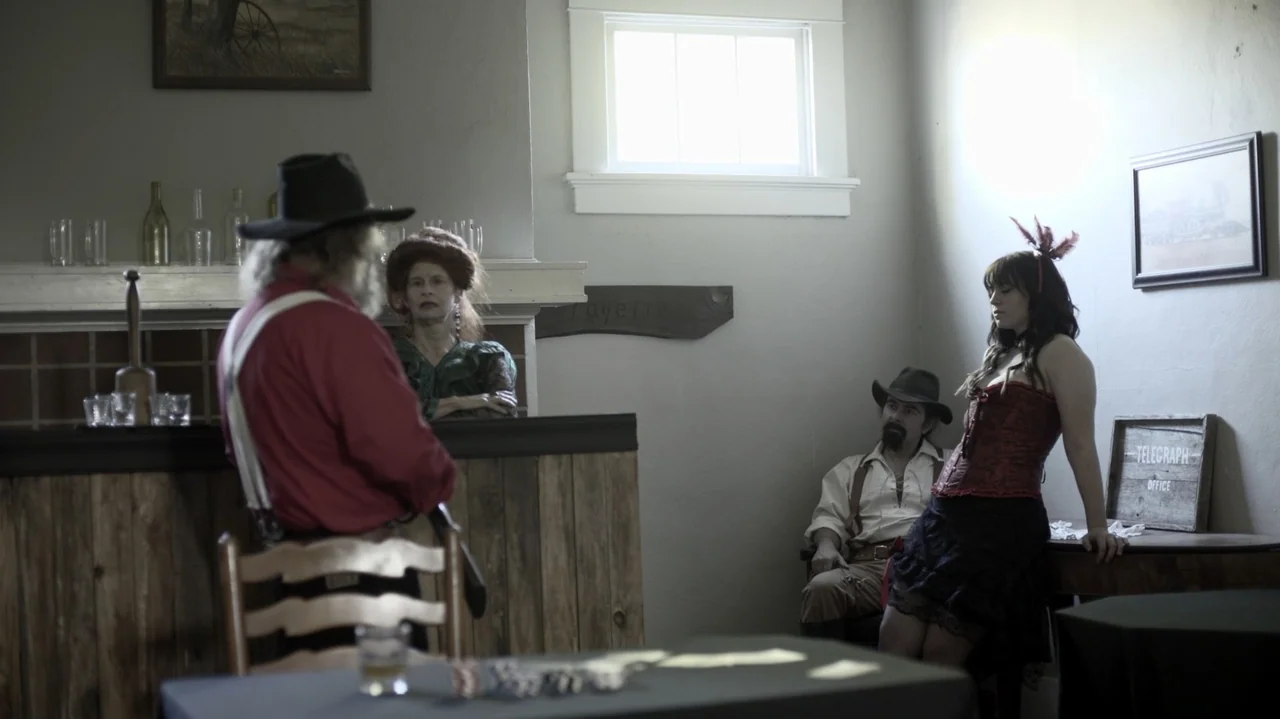 The Dalton Gang (2020) movie still: fullbody — An 1800s-style room features wooden paneling and period decor with a high small window. Four…
