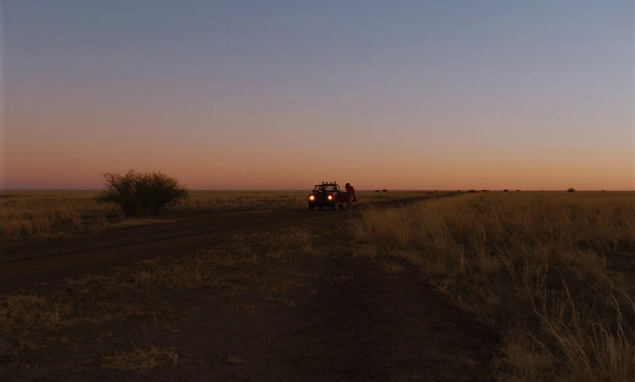 Until The End Of The World (1991) movie still: wide — A vast, flat landscape featuring a single dirt road stretching towards a colorful horizon. A…