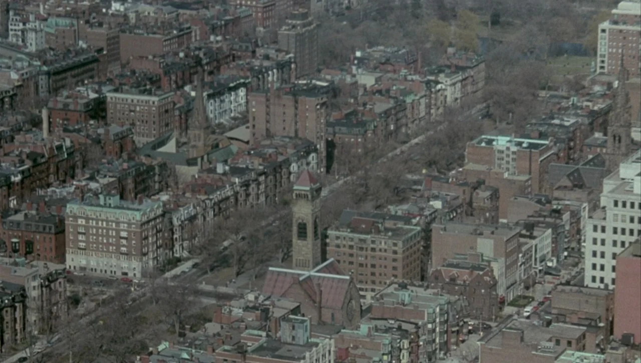 Necronomicon: Book of Dead (1993) movie still: establishing — An aerial view of a dense urban neighborhood with multi-story brick buildings and…