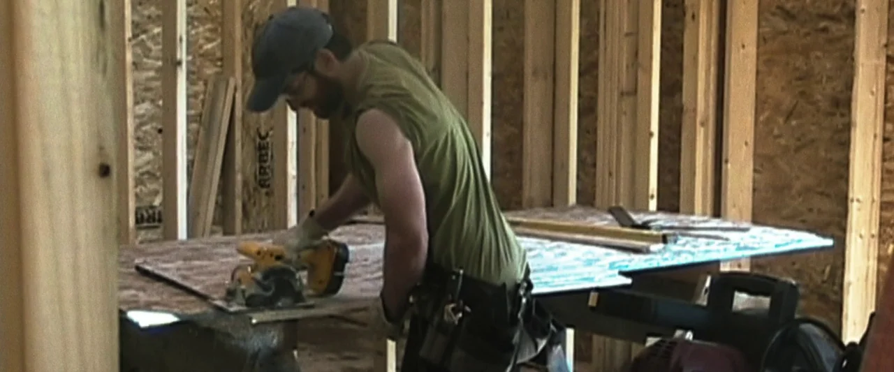 The Night House (2020) movie still: medium — A room under construction with exposed wooden wall studs and plywood sheeting. A construction worker…