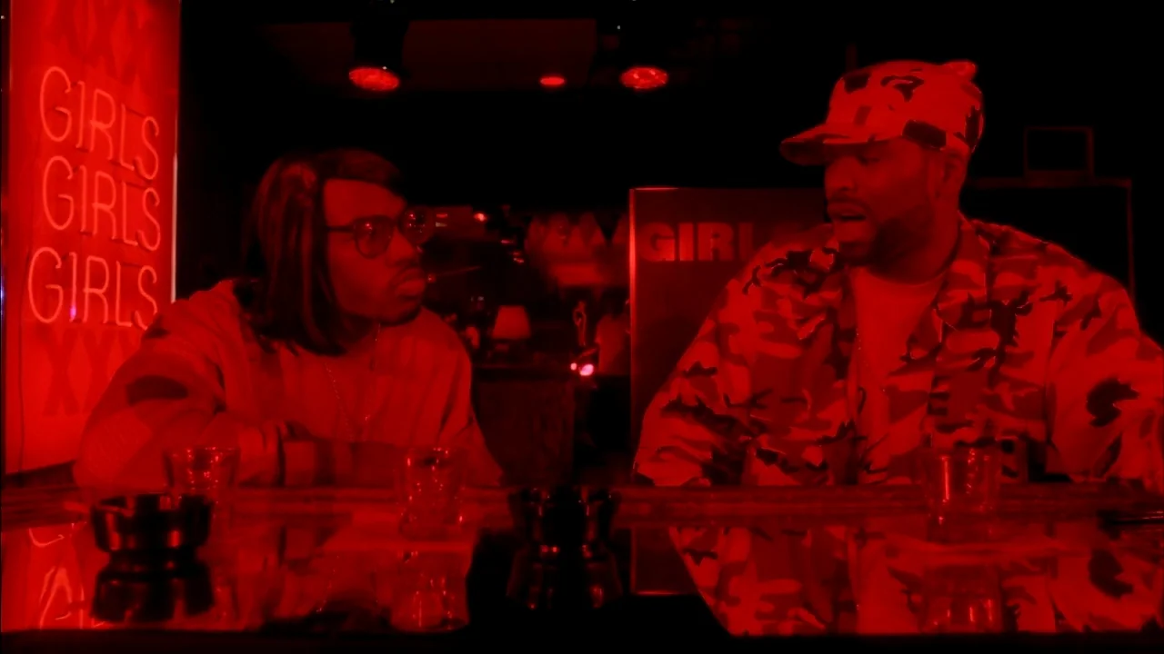 Belly (1998) movie still: medium — A dimly lit room with a reflective bar top featuring red neon signage. Two men sit at the bar engaging in a…