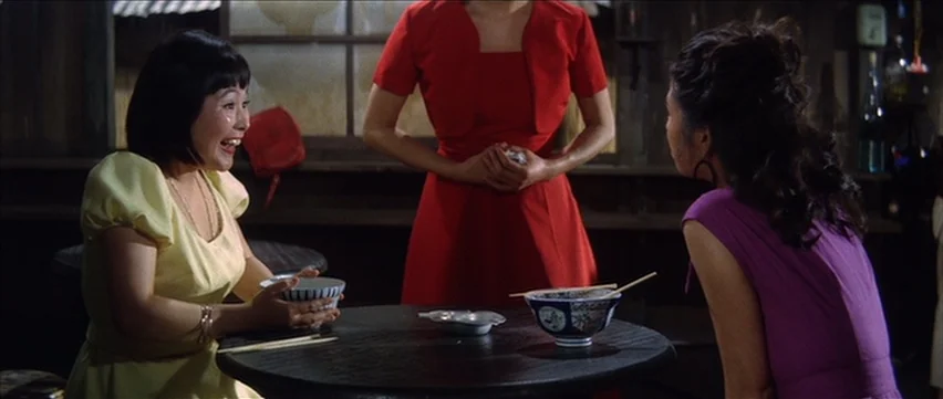 Gate of Flesh (1964) movie still: medium — A dimly lit noodle shop interior features dark wooden walls and circular tables. Three women interact…