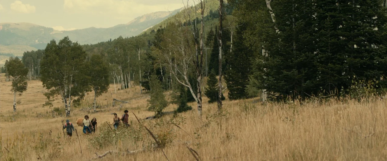 Brigsby Bear (2017) movie still: wide — A sprawling mountain meadow features dry golden grass, clusters of birch, and evergreen trees. Five young…