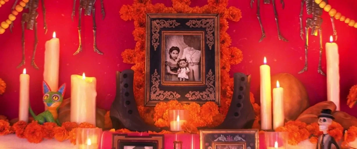 Coco (2017) movie still: medium — A vibrant red altar is covered in scattered orange marigolds and lit candles. Various framed portraits and…