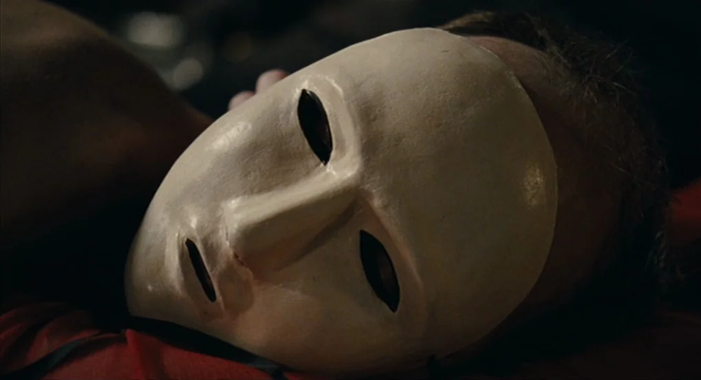 House of Tolerance (2011) movie still: closeup — A dark, dimly lit interior space with a person lying down. The focus is on a plain, featureless…