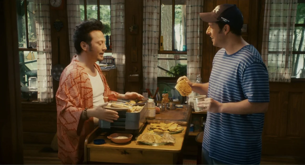 Grown Ups (2010) movie still: medium — A rustic wood-paneled room features a small table filled with plates and breakfast food. A man in a kimono…