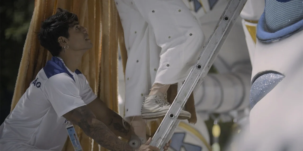 An Unforgettable Year - Summer (2023) movie still: medium — A man assists someone climbing a metal ladder attached to a decorated structure. The…