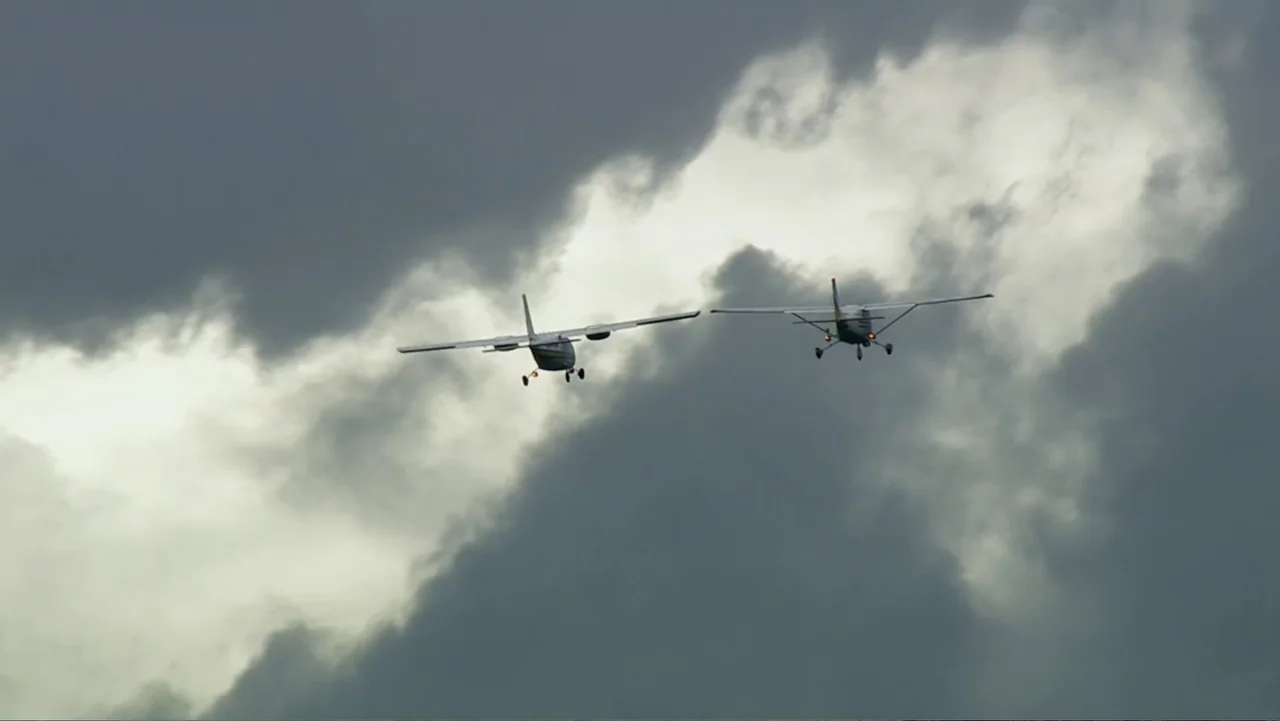 The Alps from Above: Symphony of Summits (2014) movie still: wide — Two light aircraft travel across a vast overcast sky filled with dark clouds.…