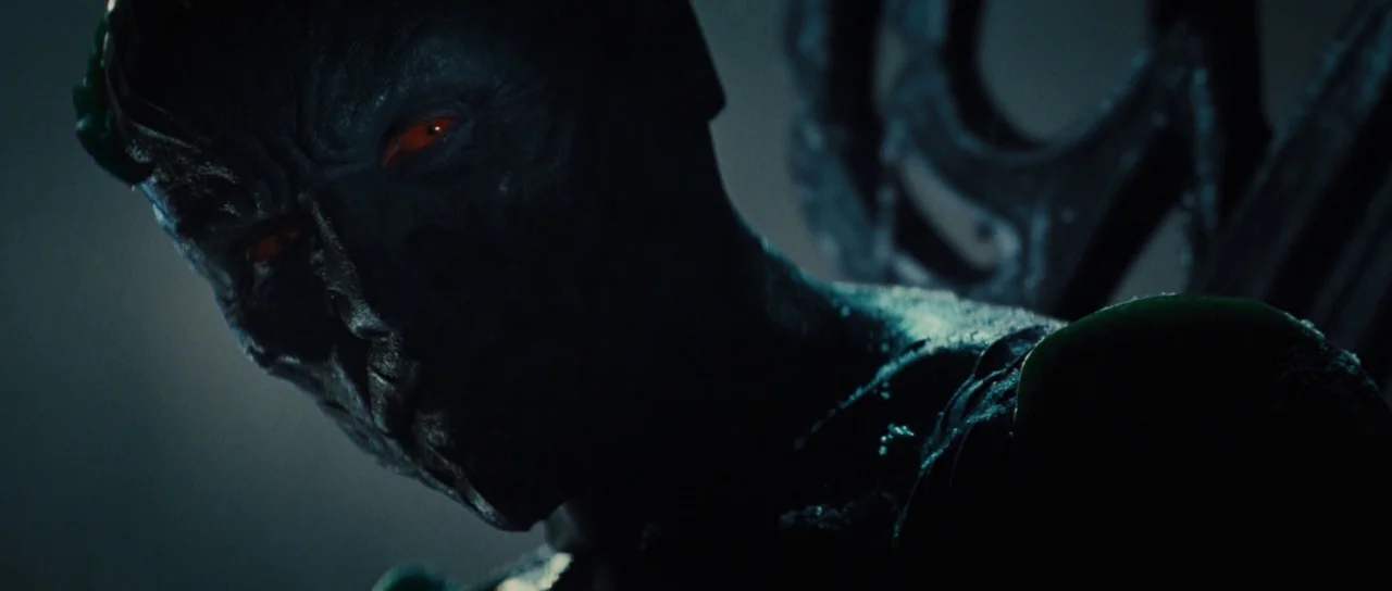 Thor (2011) movie still: closeup — A dark, dimly lit environment obscures the background details. A creature with dark, ridged skin and glowing red…