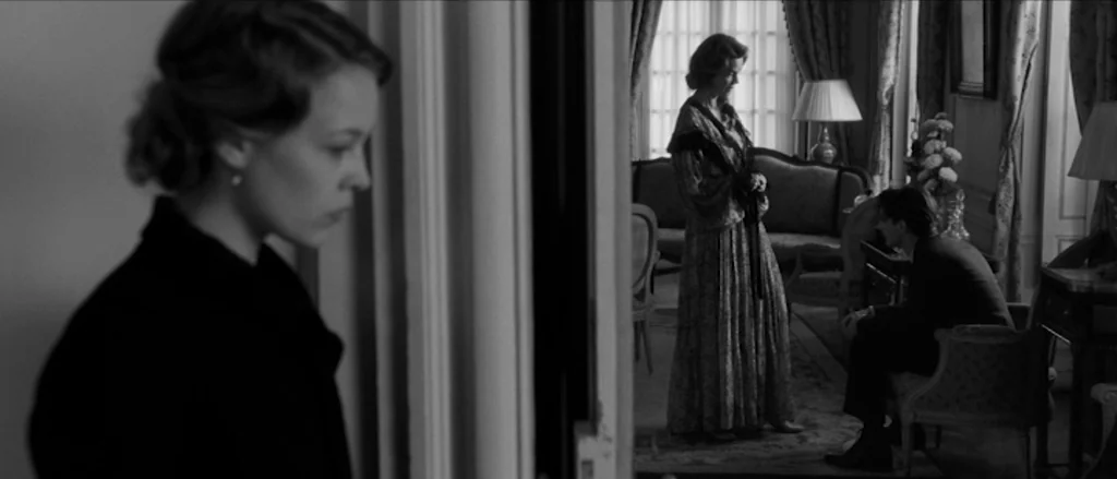 Frantz (2016) movie still: medium — A classic parlor room features ornate furniture including a sofa and patterned rug. A woman observes from a…