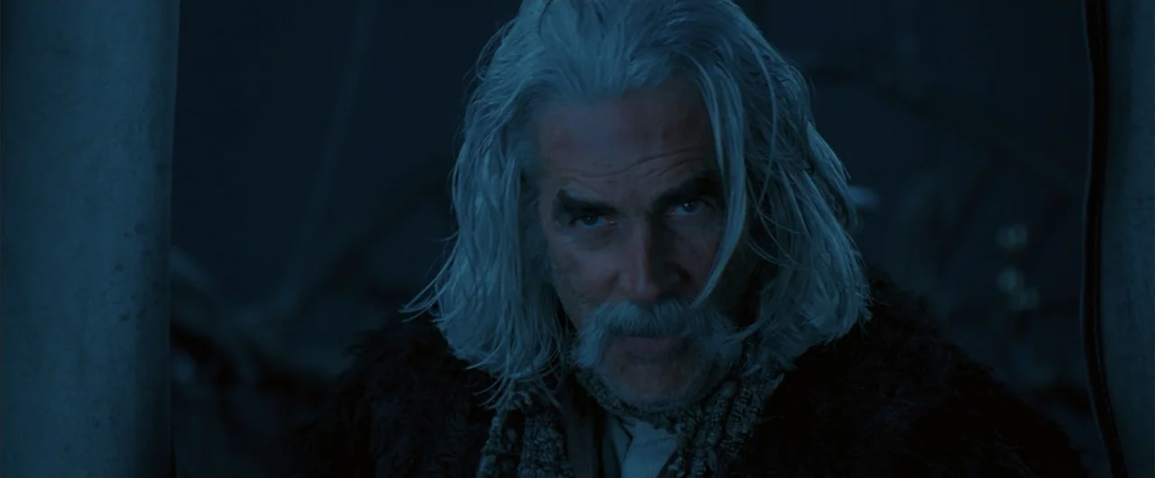 The Golden Compass (2007) movie still: closeup — An older man with long gray hair stands in a dark, outdoor setting. The subject stares ahead with a…