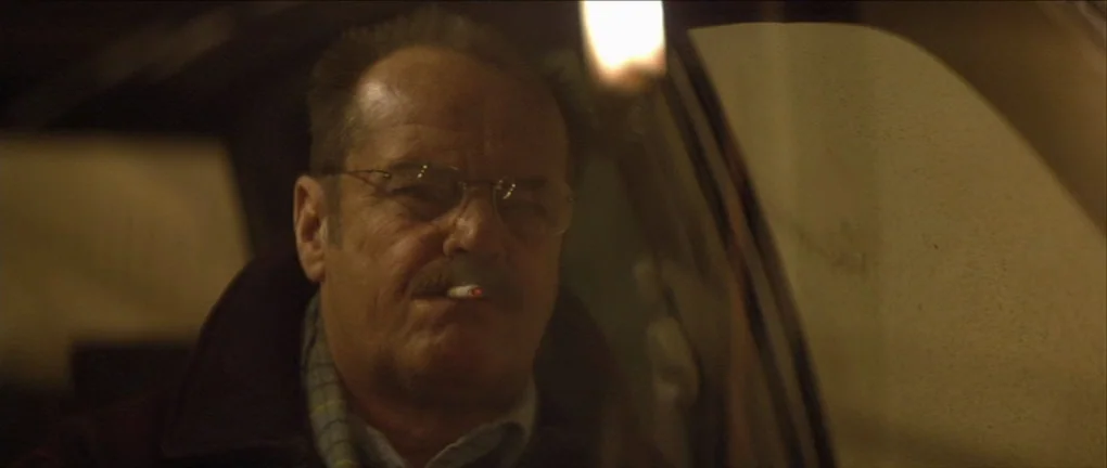 The Pledge (2001) movie still: closeup — An older man sits inside the darkened cabin of a vehicle at night. He has a lit cigarette hanging from his…