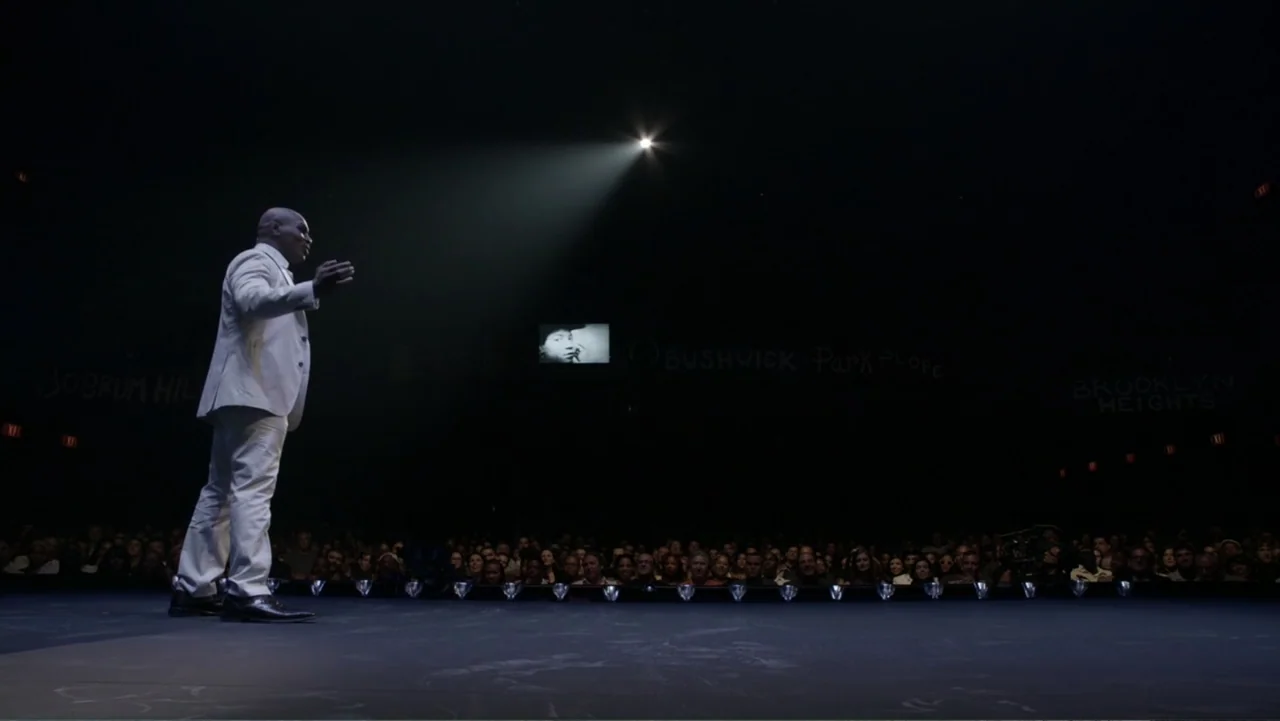 Mike Tyson: Undisputed Truth (2013) movie still: fullbody — A large dark auditorium features a solitary man centered on a minimalist stage. The man…