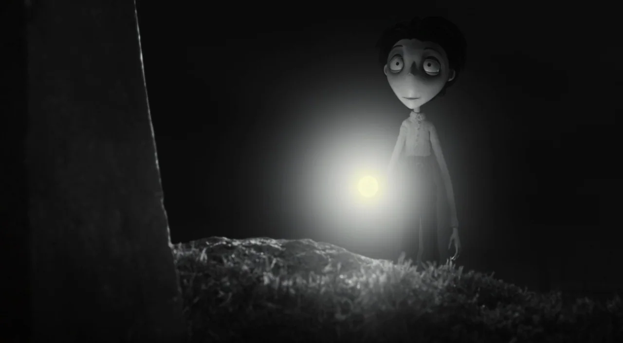 Frankenweenie (2012) movie still: medium — A dark, grassy outdoor area features a vertical stone marker on the left. The character holds a…