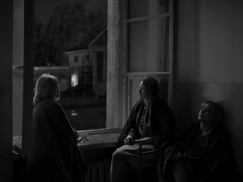 Cold War (2018) movie still: medium — A dimly lit room at night features a large window overlooking a dark exterior area. Three women sit quietly…