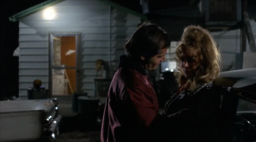 Five Easy Pieces (1970) movie still: medium — A night scene outside a small house with white wooden siding. A man and a woman stand by an open car…
