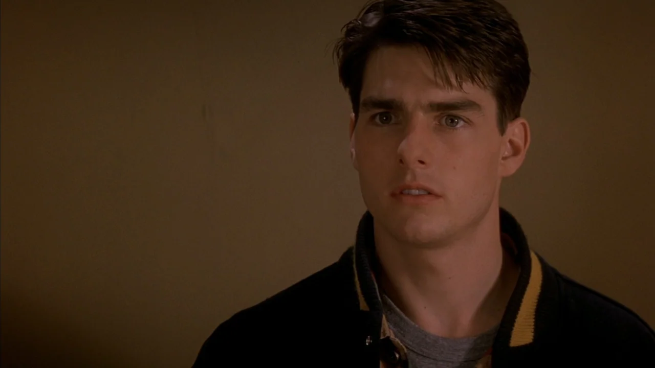 A Few Good Men (1992) movie still: closeup — A dimly lit room with plain, nondescript brown walls. A young man stares forward with a neutral gaze.