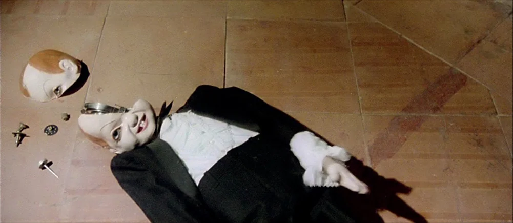 Deep Red (1975) movie still: medium — A terracotta tiled floor shows a dismantled ventriloquist dummy. The dummy's face plate is detached near small…