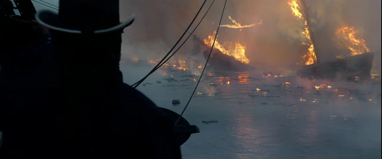 Pirates of the Caribbean: The Curse of the Black Pearl movie still: medium — A dark ocean surface reflects the glow of multiple wooden vessels…
