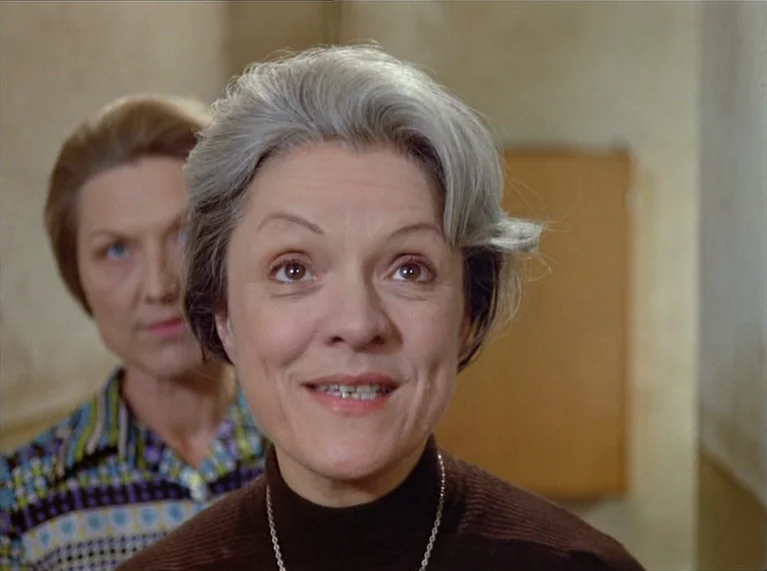 Ali: Fear Eats The Soul (1974) movie still: closeup — An interior space with plain light-colored walls and a blurred wooden object. An older woman…