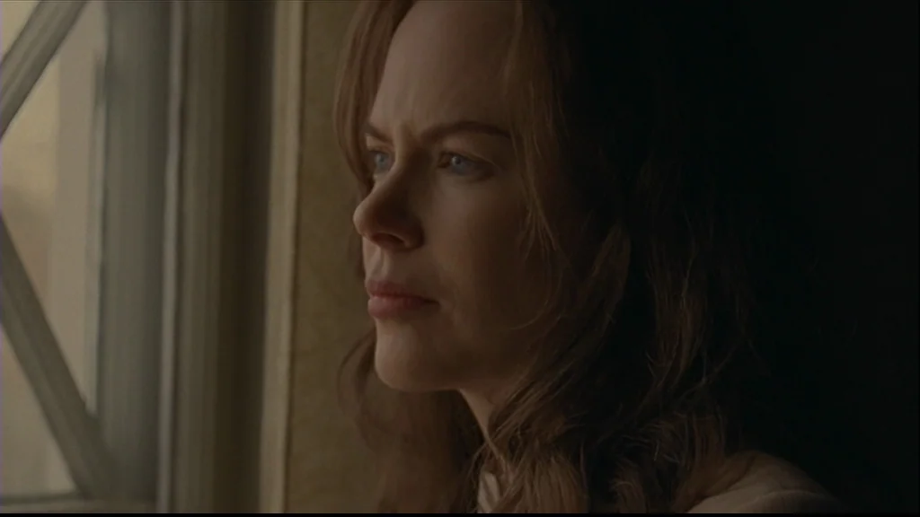 Margot At The Wedding (2007) movie still: closeup — A woman stands indoors near a wooden framed window. She looks toward the light.