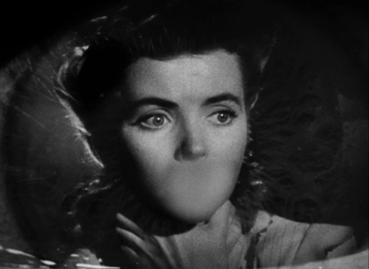 The Spiral Staircase (1946) movie still: closeup — The frame shows a close-up of a woman's face against a dark, vignette background. Her mouth is…